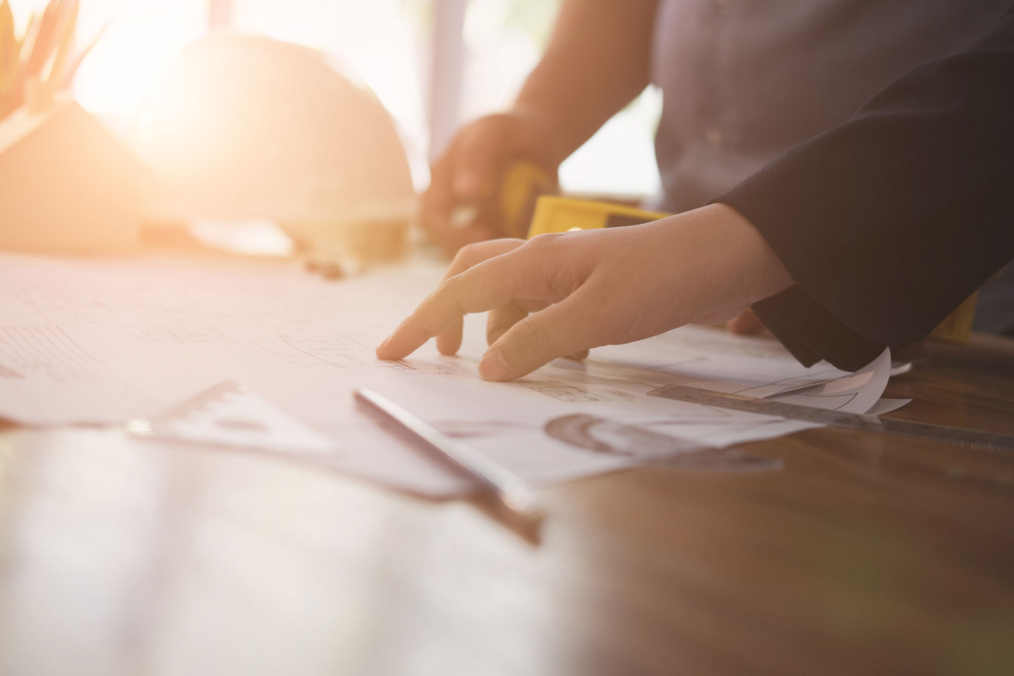 Workers look over blueprints with lens flare