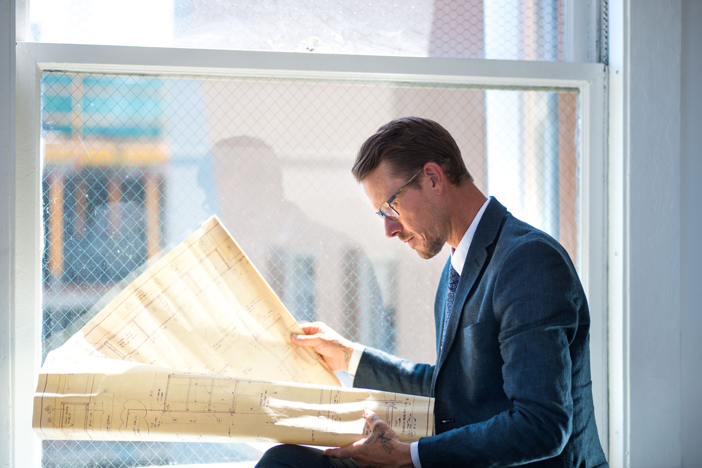 A businessman wearing glasses looks over house blueprints