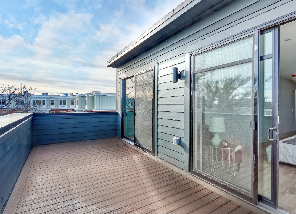 Balcony of a blue house with double sliding glass doors