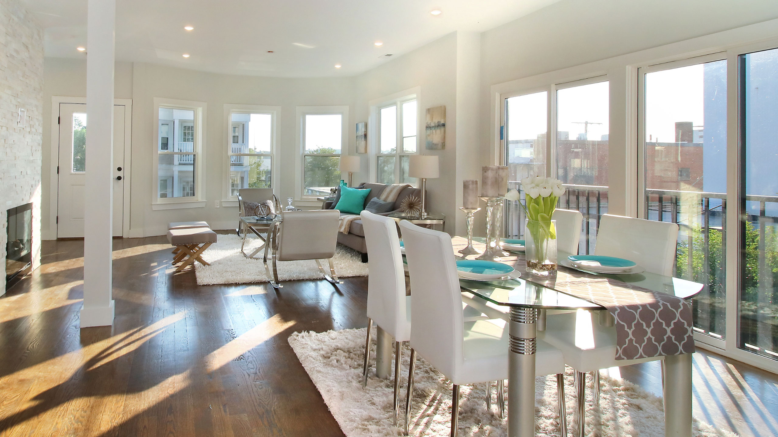 Open dining and living area with wood floors and white balcony door