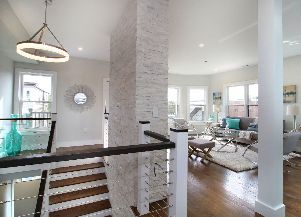 Stairs leading up to living area with white brick fireplace